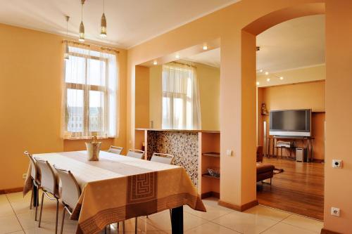 comedor con mesa, sillas y TV en Raina Lux Apartment, en Riga