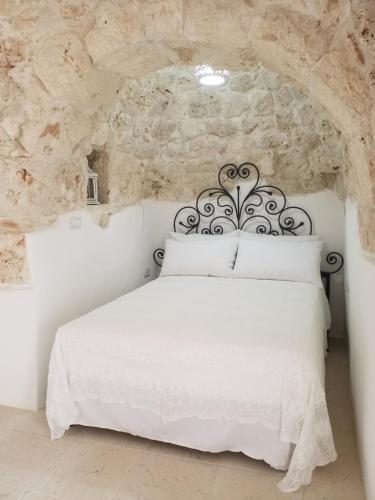 1 dormitorio con 1 cama blanca en una pared de piedra en I Trulli Di Spinaruta en Grottaglie