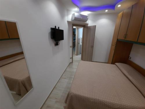 Cette chambre comprend 2 lits et une télévision murale. dans l'établissement GUEST HOME, à Ischia