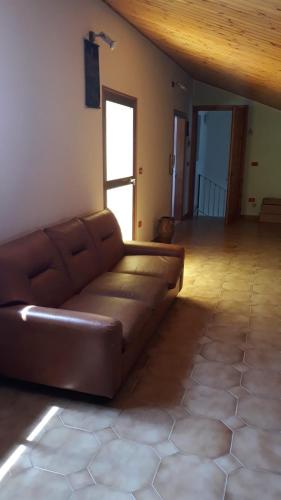 um sofá de couro castanho numa sala de estar com tecto de madeira em Casa vacanza a Campolieto em Campolieto