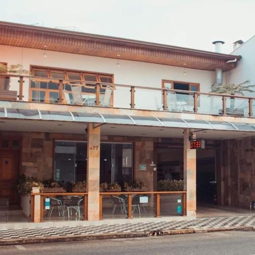 a building with a balcony with tables and chairs at Hotel Garrafão - Rua Principal de Boituva in Boituva