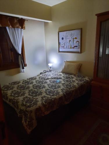 - une chambre avec un lit et une couverture dans l'établissement Charmoso Apartamento em Gramado, à Gramado