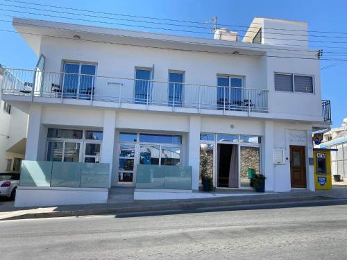 a white building with a balcony on a street at ElleNapa Apts & Studios in Ayia Napa