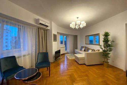 Una sala de estar con un sofá, una mesa y sillas. en New Luxury Flat in front of the Parliament at Unirii, en Bucarest