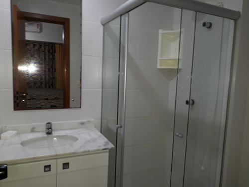 a bathroom with a shower and a sink and a mirror at Praia do Forte Estúdio in Praia do Forte