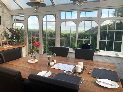 a dining room with a table with chairs and windows at Ty Capel in Llanidloes