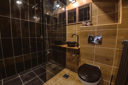 een zwart betegelde badkamer met een toilet en een wastafel bij Loft Apartman Menhetn in Šabac