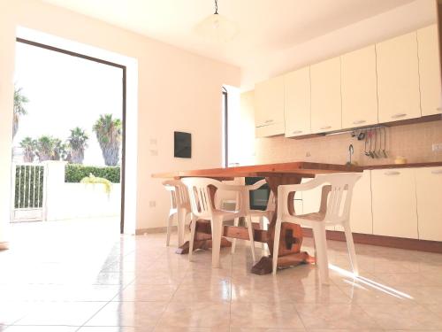 a kitchen with white cabinets and a wooden table and chairs at villa Lina in Capilungo