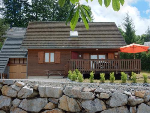 une petite maison avec une véranda et un parasol dans l'établissement Peaceful Chalet in Beaulieu with Whirlpool, à Beaulieu