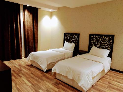 two beds in a hotel room with white sheets at شقق درر رامه للشقق المخدومة 6 in Riyadh
