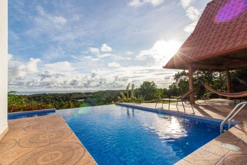 a swimming pool with two chairs and an umbrella at Casa Unicornio Azul in Uvita