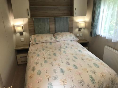 a bedroom with a bed with a comforter on it at Luxury 3 Bedroom Caravan MC37, Shanklin, Isle of Wight in Shanklin