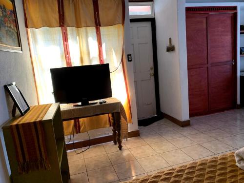 a living room with a tv on a table and a door at Villas JABEL TINAMIT in Panajachel