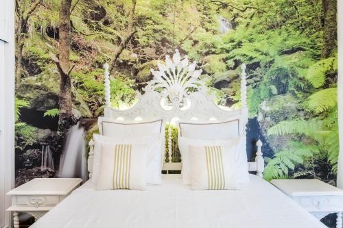 1 dormitorio con cama blanca y pared de árboles en Apartamento Princesa Madeira, en Funchal