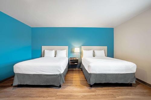 WoodSpring Suites Naples في نيبلس: سريرين في غرفة بجدران زرقاء