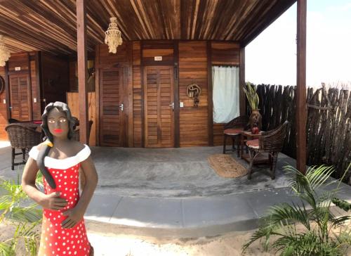 a girl in a red dress standing in front of a house at Pousada Portal do Kite in Tatajuba