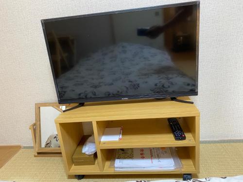a flat screen tv on a wooden stand with a remote control at Hotel EL Shinjuku 6 in Tokyo