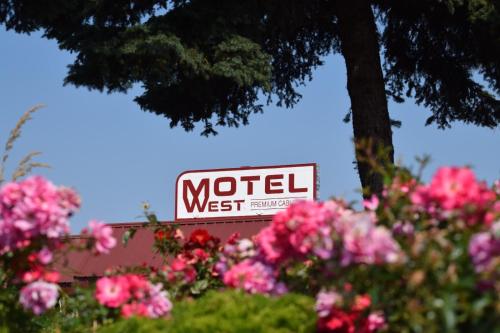 a sign for a motel next to pink flowers at Motel West in Bend