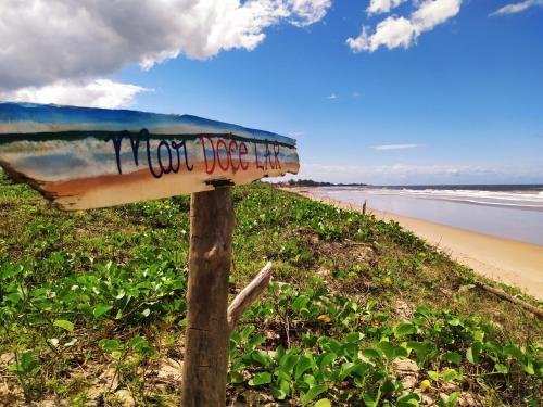 a sign sitting on the side of a beach at MAR DOCE LAR - Praia de Sossego in São Francisco de Itabapoana