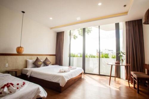 a hotel room with two beds and a large window at Luu Ngai Condotel Quy Nhon in Quy Nhon
