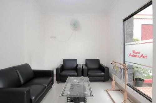 a waiting room with black leather chairs and a table at RedDoorz at Andalas Asri Lampung in Bandar Lampung