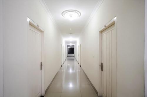 a long hallway with white walls and white doors at RedDoorz at Andalas Asri Lampung in Bandar Lampung