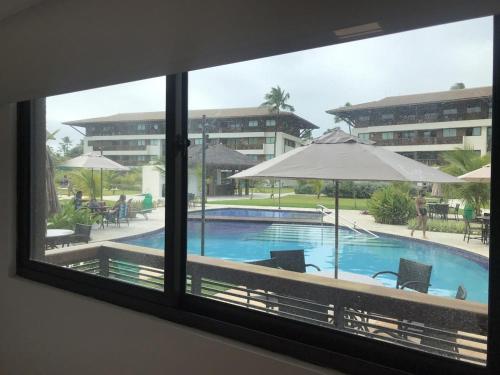 uma vista para uma piscina através de uma janela em Cupe Beach Living Flat em Porto de Galinhas
