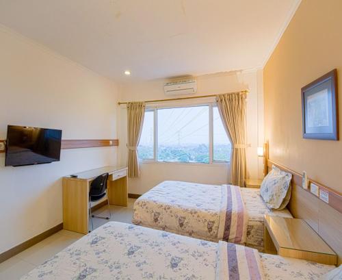 a hotel room with two beds and a television at Citrus-House com Hotel in Bogor