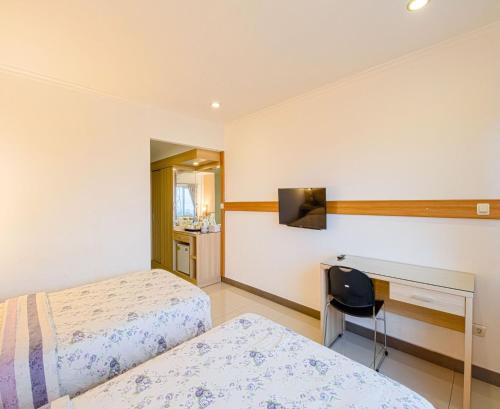a hotel room with two beds and a desk at Citrus-House com Hotel in Bogor