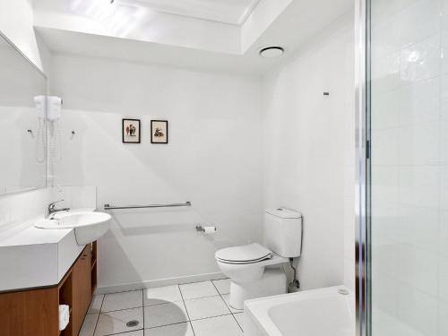 a white bathroom with a toilet and a sink at Apartment 26 Pacific Apartments in Lorne