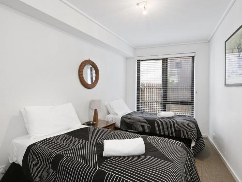 two beds in a room with a window at Apartment 26 Pacific Apartments in Lorne
