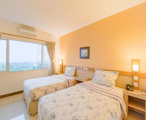 a hotel room with two beds and a window at Citrus-House com Hotel in Bogor