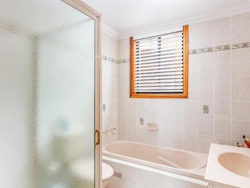 a bathroom with a tub and a sink and a toilet at Allure On Seven Mile Beach Gerroa in Gerroa