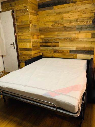 a bed in a room with a wooden wall at Charmant petit appartement à Grimentz au pied des pistes in Grimentz