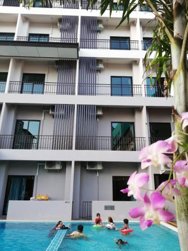 a group of people swimming in a swimming pool in front of a building at J.P.GRAND HOTEL in Trat