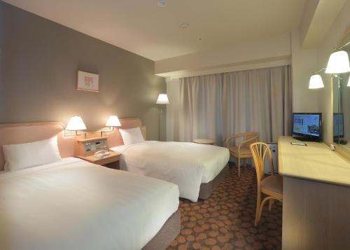 福井市にあるホテルフジタ福井のベッド2台とデスクが備わるホテルルームです。