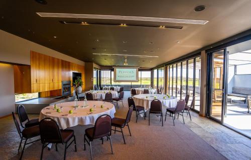 a banquet hall with tables and chairs and a screen at Peppers Moonah Links Resort in Fingal