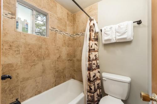 a white toilet sitting next to a bath tub in a bathroom at 4 Seasons Inn on Fall River in Estes Park