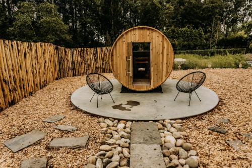 a circular wooden building with two chairs in a yard at Fiertelmeers Boutique B&B in Ronse