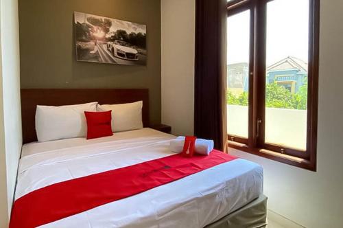 a bedroom with a large bed with red sheets and a window at RedDoorz Syariah At Pucang Anom in Surabaya