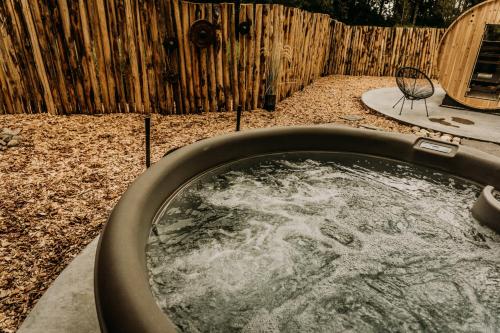 a bath tub with water in it next to a wooden fence at Fiertelmeers Boutique B&B in Ronse