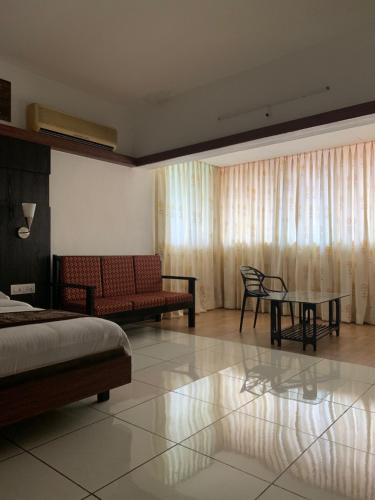 1 dormitorio con cama, sofá y mesa en Honeybee Resort, en Lonavala