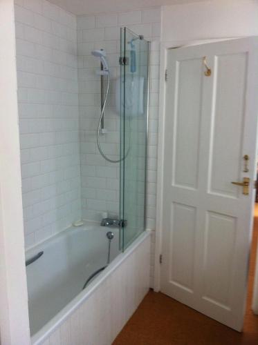a bathroom with a tub and a glass shower at Tremanhire Cottage in Solva