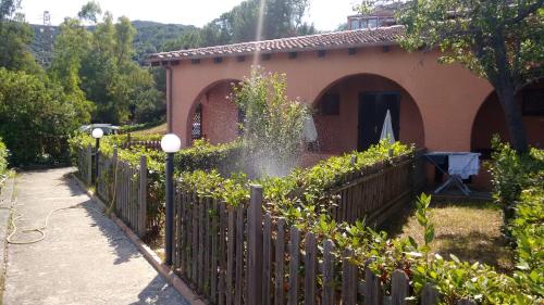a fence in front of a house with a garden at Resort Le Picchiaie in Portoferraio