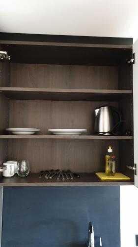 a kitchen with a shelf with dishes on it at FÜ Hotel by WMM Hotels in Fürth