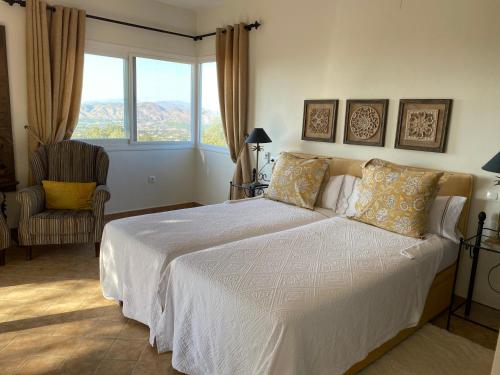een slaapkamer met een bed, een stoel en een raam bij Finca Sonrisa in Alhaurín el Grande