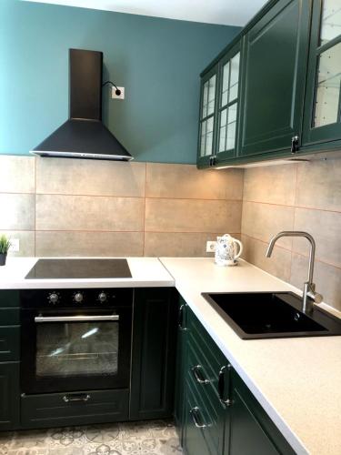 a kitchen with green cabinets and a sink at Green and quiet city center in Rīga