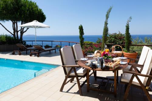 een eettafel en stoelen naast een zwembad bij Villa Noria in Aghia Marina