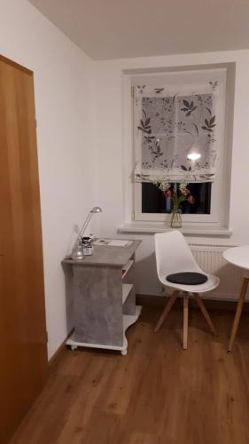 Habrachćicy的住宿－gemütliche Ferienwohnung in der Oberlausitz，窗户客房内的一张桌子和一把椅子