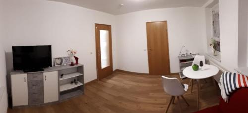 een woonkamer met een tv en een tafel en een stoel bij gemütliche Ferienwohnung in der Oberlausitz in Habrachćicy